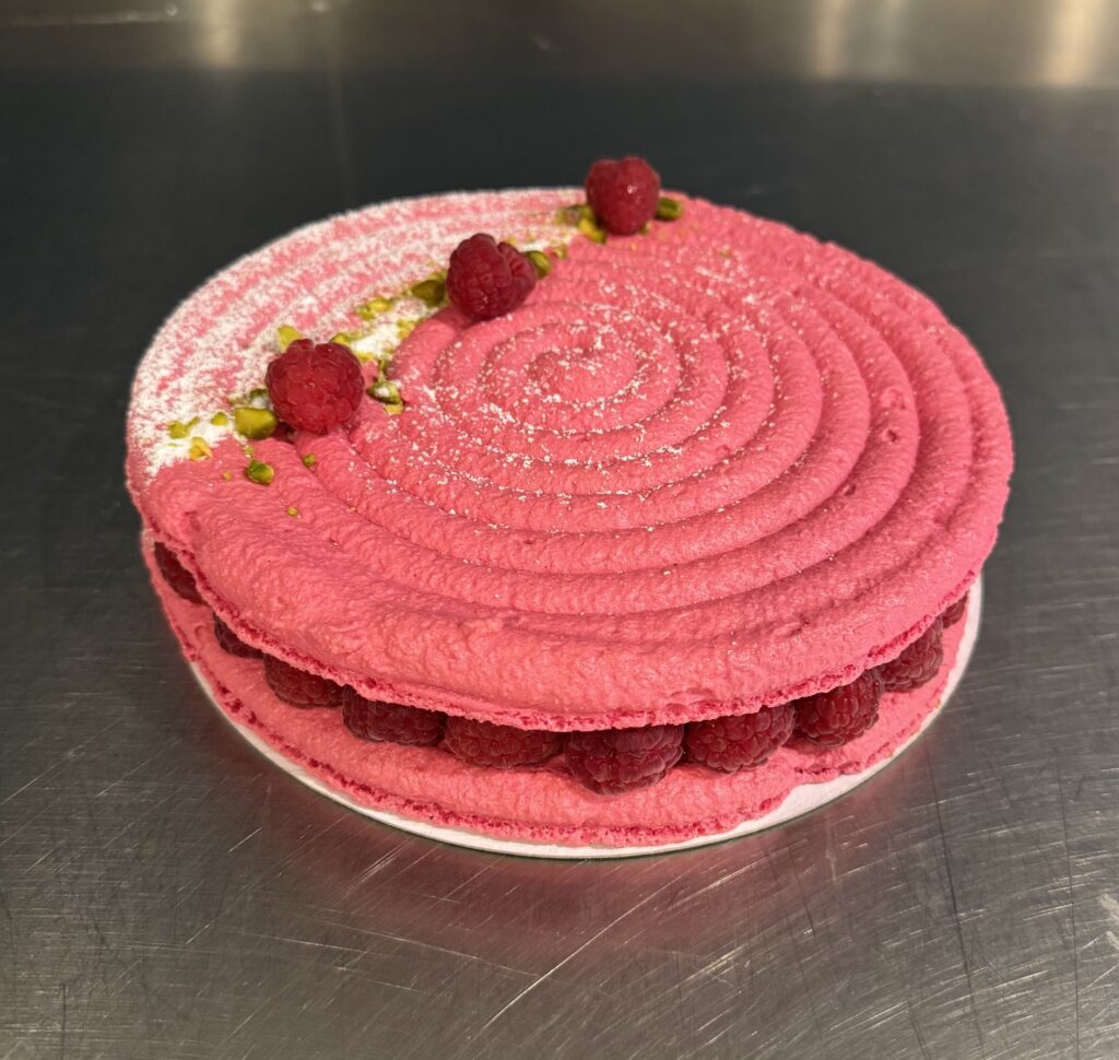 La délicatesse du macaron associée à une crème mousseline onctueuse, un confit de framboises intense et des framboises fraîches.